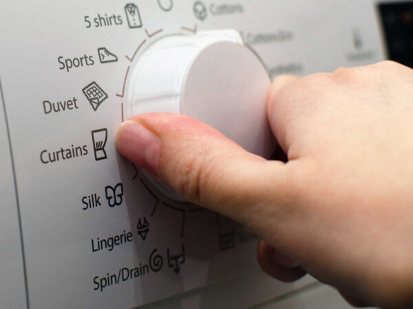 Hand turning the dial on washing machine settings