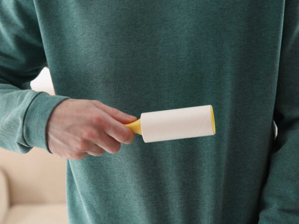 Lint-free clothes – Man using a lint roller on his jumper