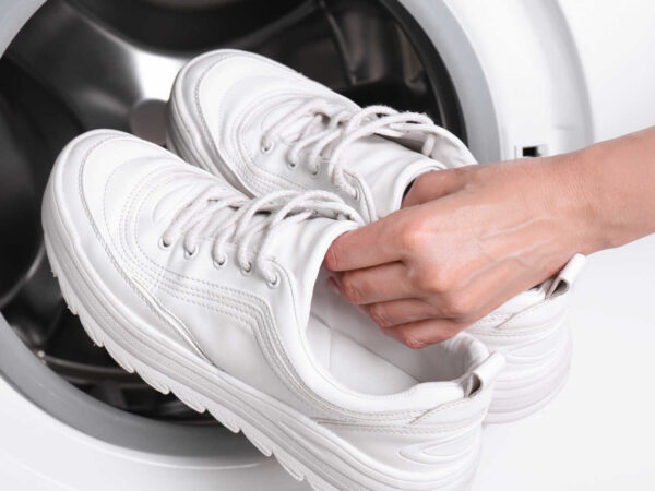 Image Alt Text Washing shoes at laundromat – person pulling clean shoes out of washing machine