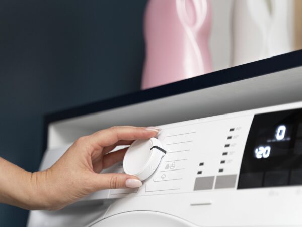 Woman choosing a program on washing machine for sustainable laundry practices