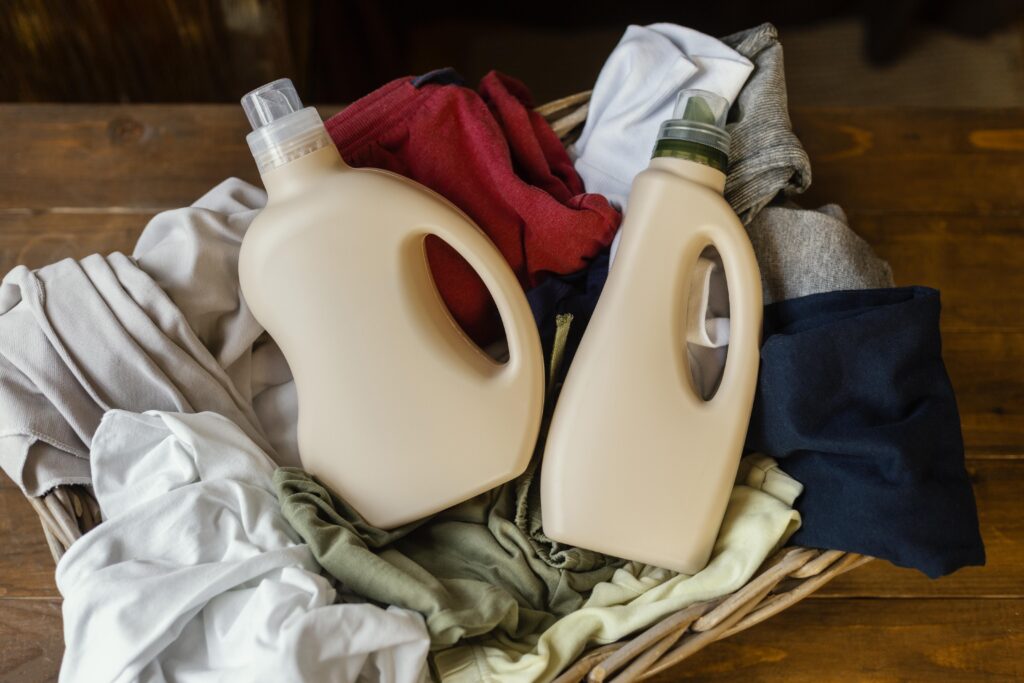 Detergent bottles laying on top of a clean pile of clothes