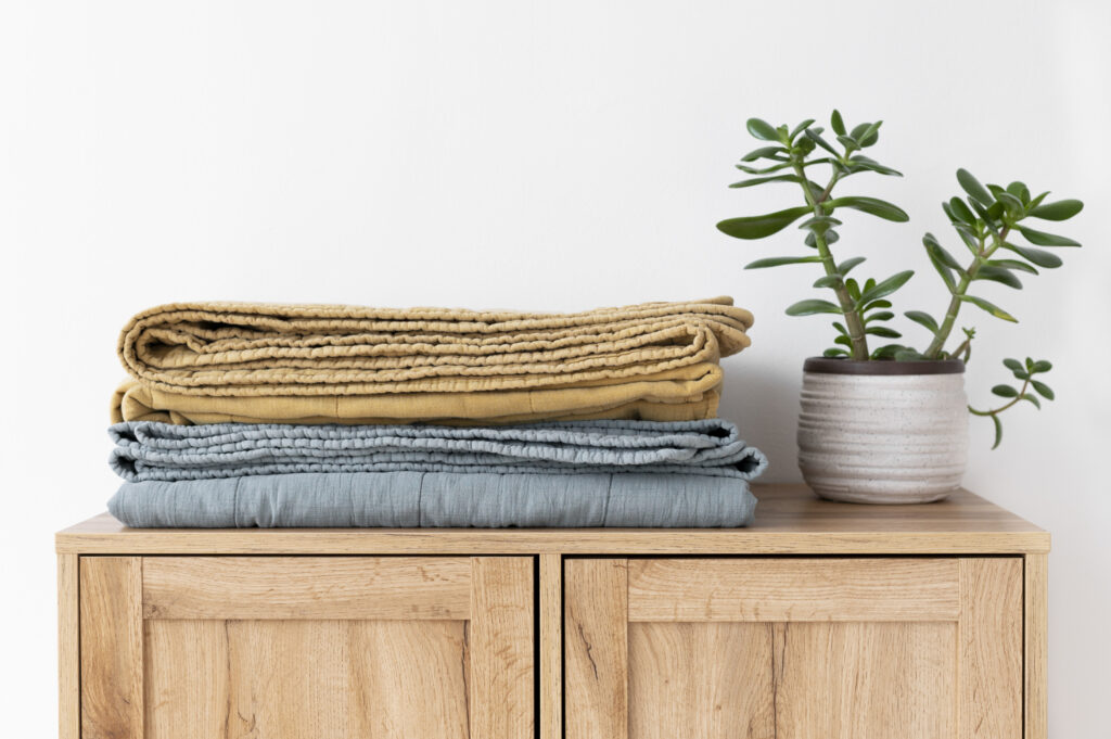 Folded clean, cosy textured blankets on a wooden cupboard