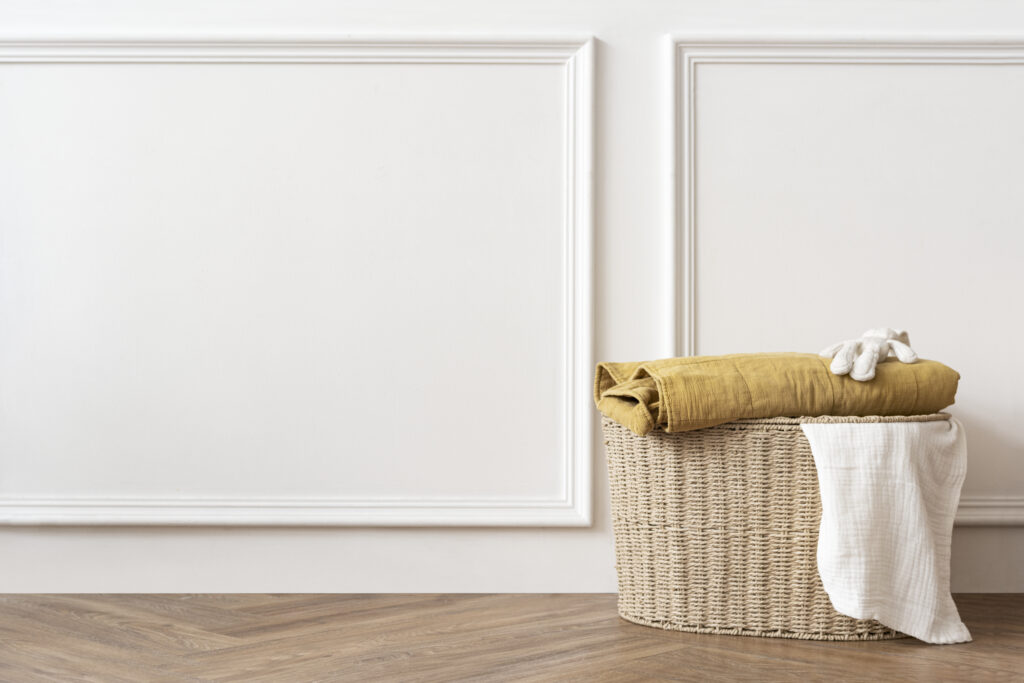 A rattan laundry basket with blanket in a stylish white room