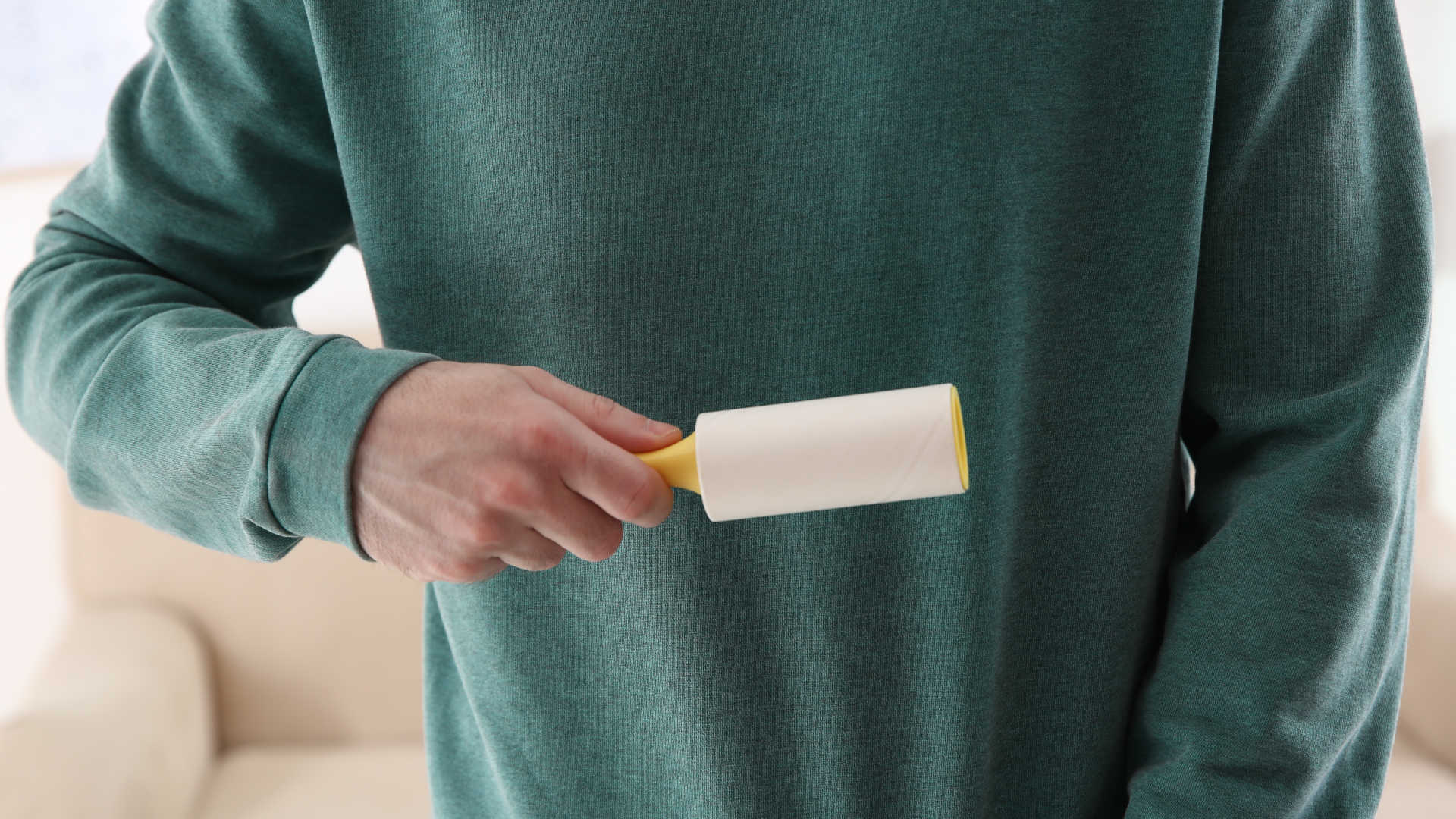 Lint-free clothes – Man using a lint roller on his jumper