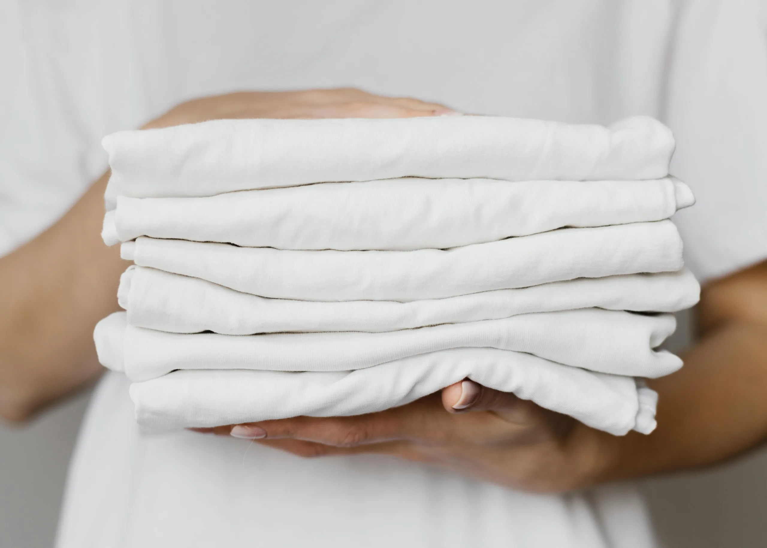 A person holding a folded white clothes